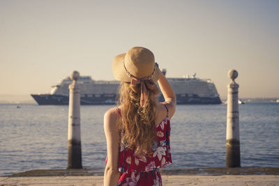 Rear view of woman standing on pier over sea 