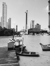 Boats moored in city by buildings against sky