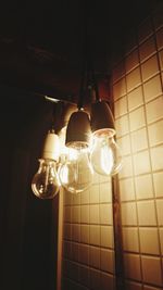 Low angle view of illuminated light bulbs hanging at night