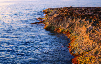 Sunrise over the rocks at the edge of the sea, sliema city, malta