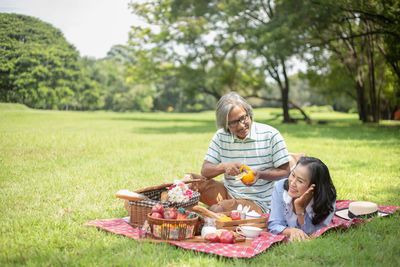 Rear view of mother and daughter in basket on grass