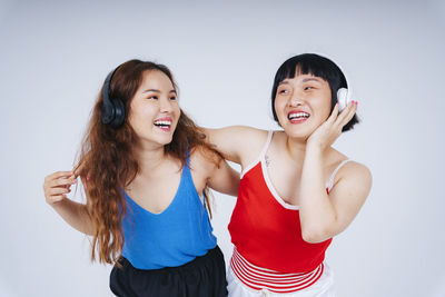 Lesbian couple listening music against gray background