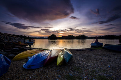 Boats moored on lake against sky during sunset
