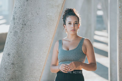 Portrait of young woman standing against wall