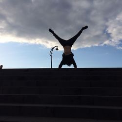 Full length of man with arms raised against sky