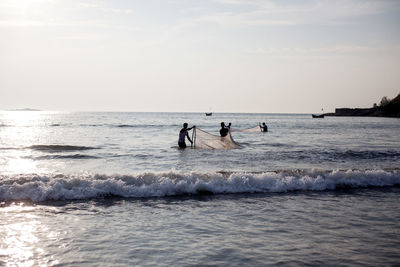 People fishing in sea against clear sky