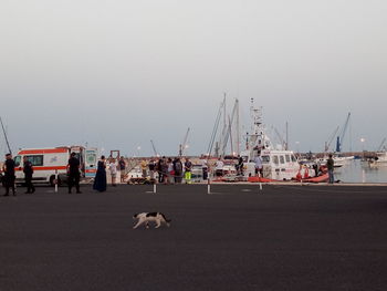 People on harbor against clear sky