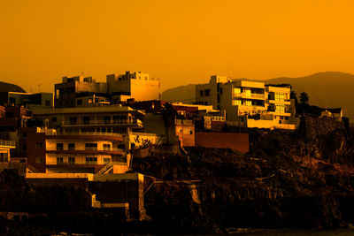 Buildings in city against orange sky