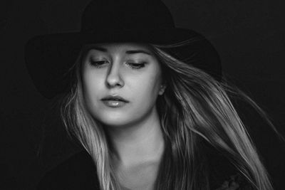 Portrait of young woman against black background