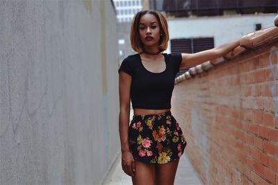 Portrait of beautiful young woman standing against wall