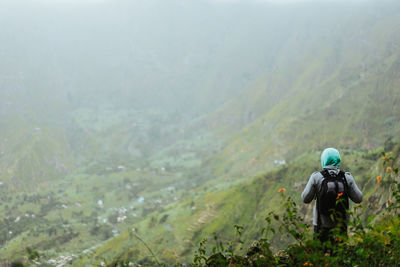 Rear view of mature man with backpack standing on mountain