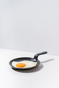 Delicious fried egg on black skillet served on table on white background in studio