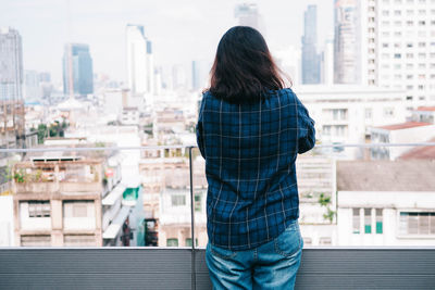 Rear view of woman standing against buildings in city