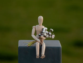 Close-up of human figurine with flowers on table