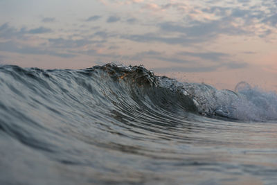 Close-up of wave on shore against sky during sunset