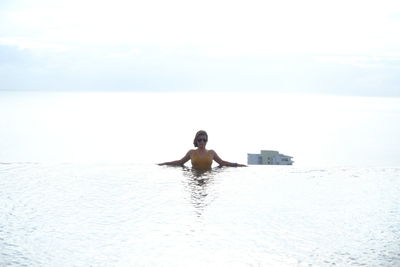 Full length of man in swimming pool against sea