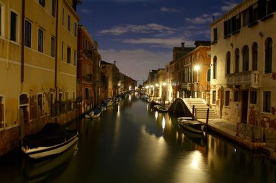 Boats moored in canal amidst buildings in city