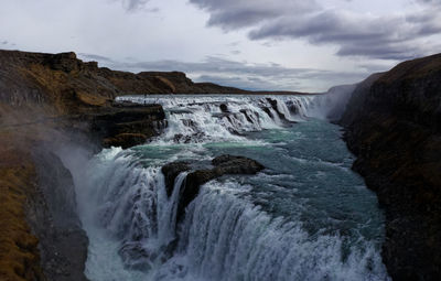 Scenic view of waterfall by sea against sky