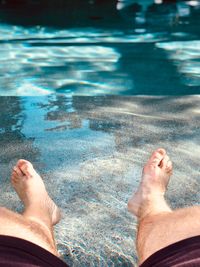 Low section of man relaxing in sea at beach