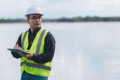 Portrait of young man standing by lake