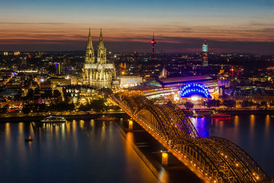 Aerial view of illuminated bridge over river in city at night