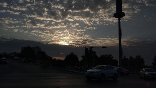 Cars on street against sky during sunset