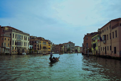 Canal amidst buildings in city against sky