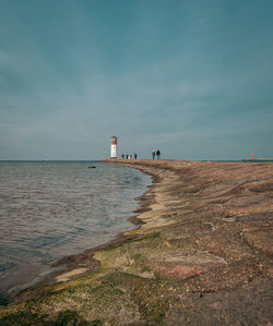 Lighthouse by sea against sky