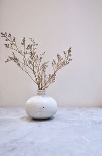 Close-up of white vase on table against wall