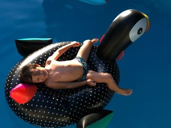 High angle view of boy on inflatable penguin in swimming pool