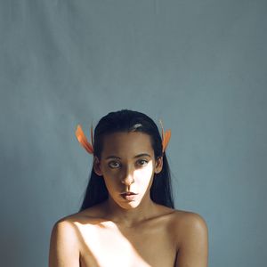 Portrait of shirtless young woman against gray background