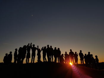 Silhouette people standing against clear sky during sunset