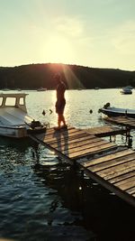 Silhouette man in lake against sky during sunset