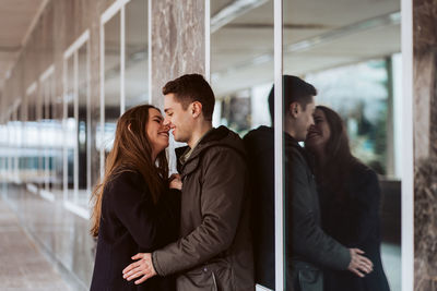 Young couple embracing against window