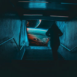 Rear view of man standing on staircase in subway