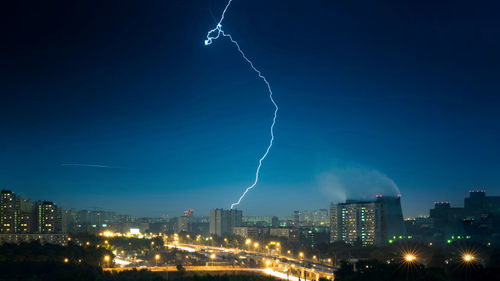 View of lightning over illuminated city against sky at night