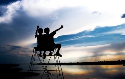 Silhouette people sitting against sky during sunset