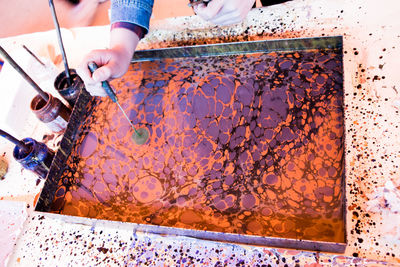 Cropped hand of person making acrylic painting on table