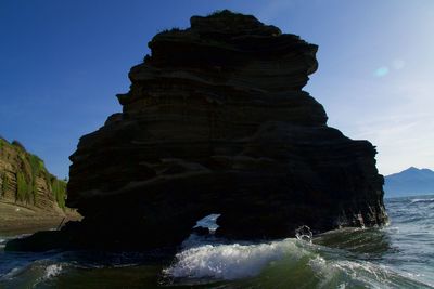 Rock formation on sea shore against sky