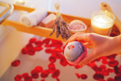 Putting bath bomb into spiritual aura cleansing flower bath for full moon ritual with candles, salt