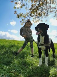 Woman with dog on field against sky