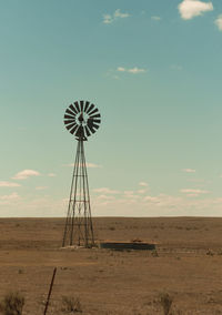 Windmill on land against sky