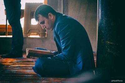 Side view of young man sitting on book