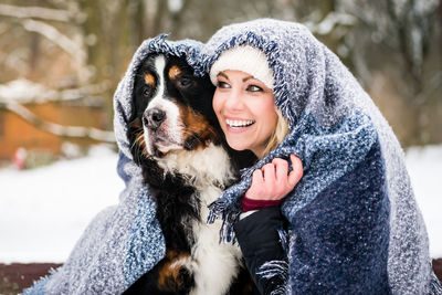 Happy woman with dog under blanket during winter