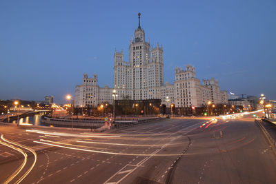 Illuminated city street and buildings against sky