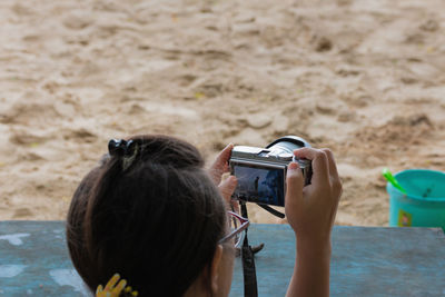 Rear view of woman photographing at beach