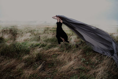 Woman holding gray shawl on grassy field