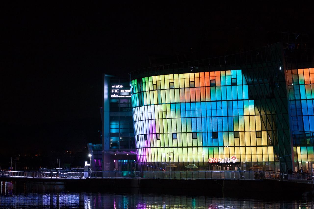 architecture, built structure, building exterior, night, city, illuminated, modern, building, reflection, text, clear sky, western script, communication, office building, no people, outdoors, waterfront, blue, low angle view, water