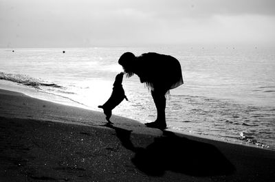 Silhouettes of woman and dog on beach