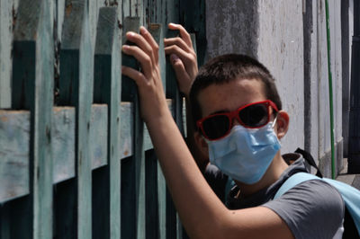 Portrait of boy wearing sunglasses standing by gate